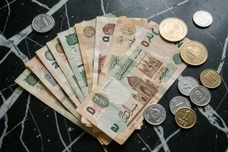 Billets et pièces de dirham des Émirats arabes unis disposés sur une surface en marbre sombre